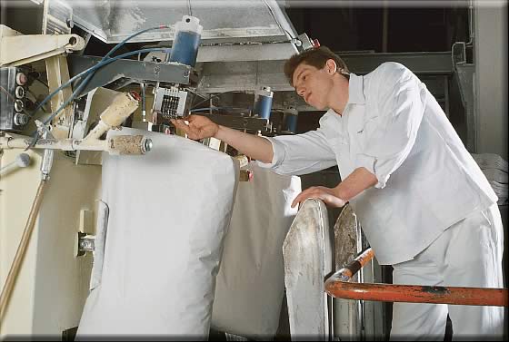 Ein Mann überwacht das maschinelle Abfüllen von Mehl in weiße Säcke